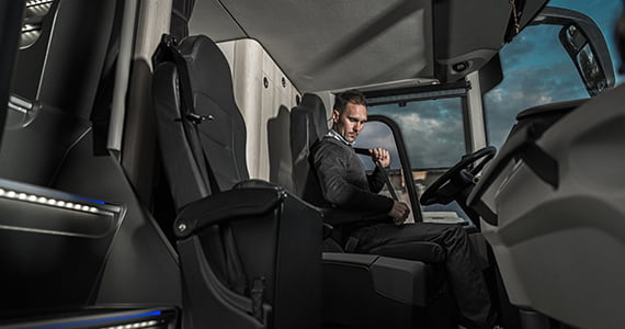 A bus driver buckles a seatbelt in the driver seat of a charter bus